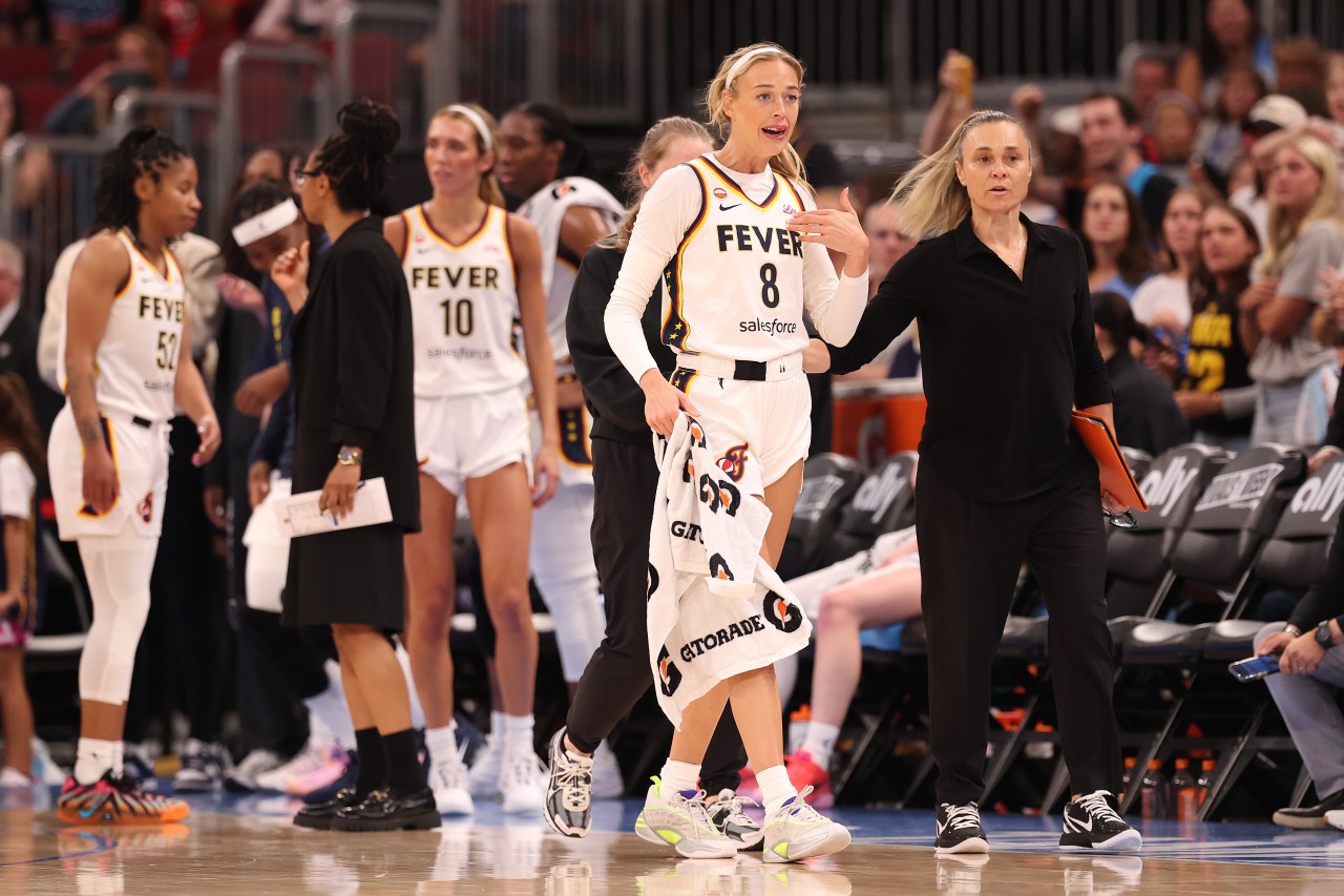 Indiana Fever's Sophie Cunningham (#8) walks along the sideline with head coach Stephanie White and teammates after a scuffle.