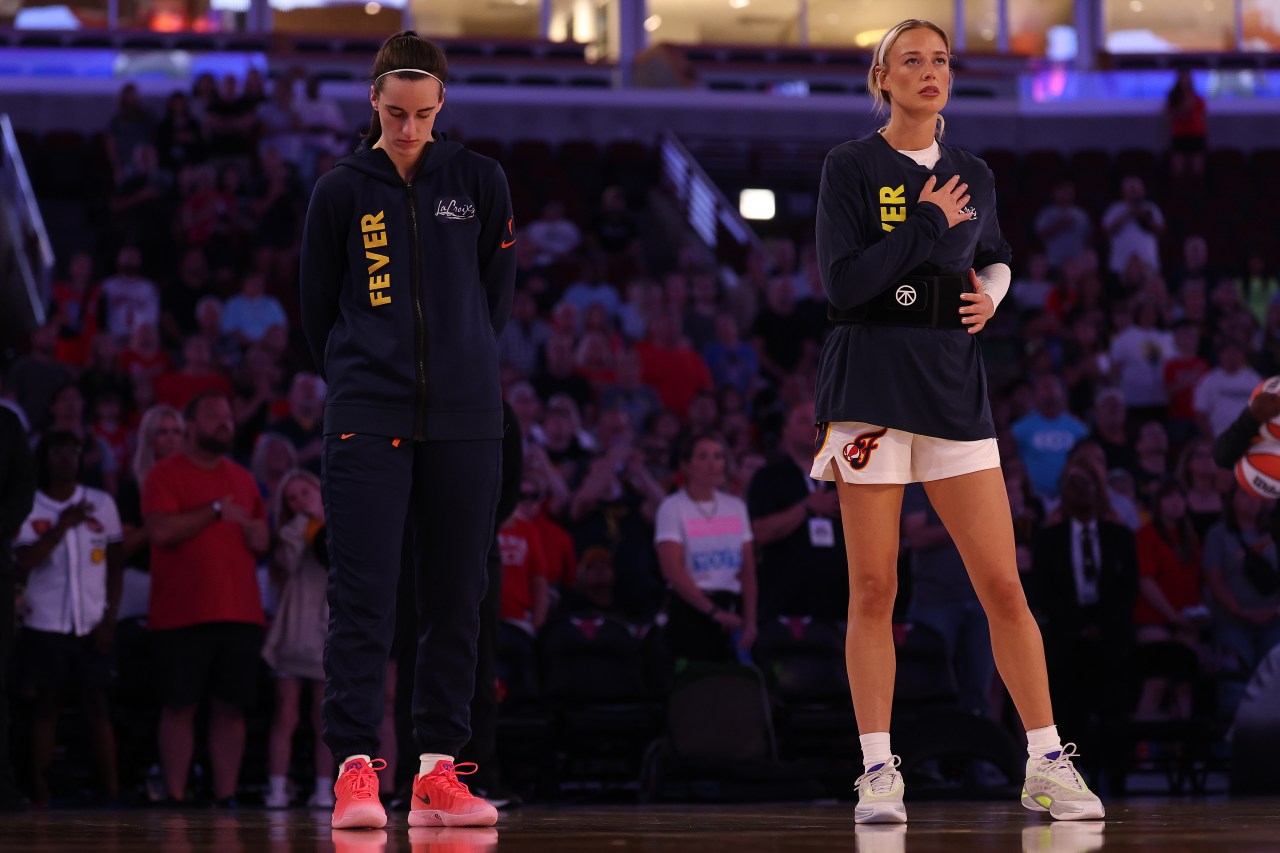 Two Indiana Fever players in navy warmup gear stand on court during the national anthem before a WNBA game at United Center.