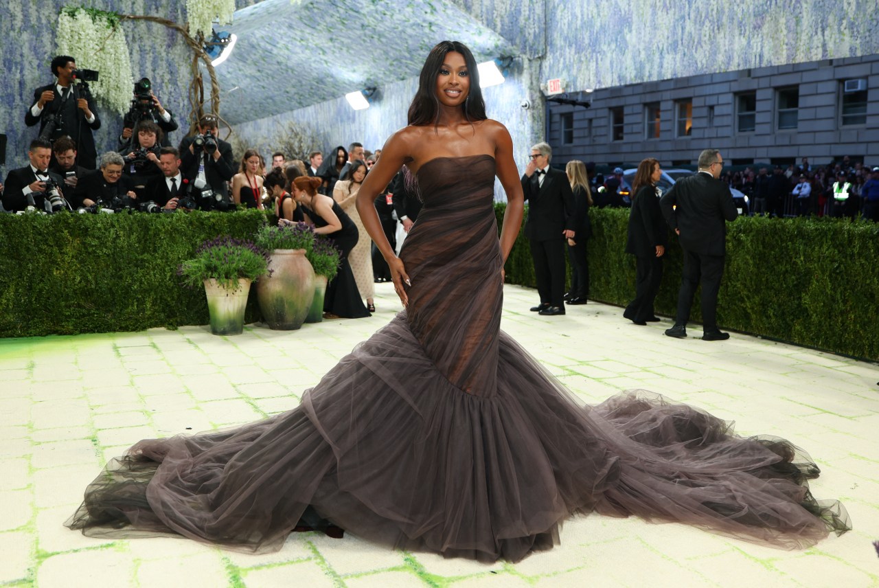 Coco Jones wearing a strapless dark brown tulle ball gown with a long ruffled train on the Met Gala red carpet.