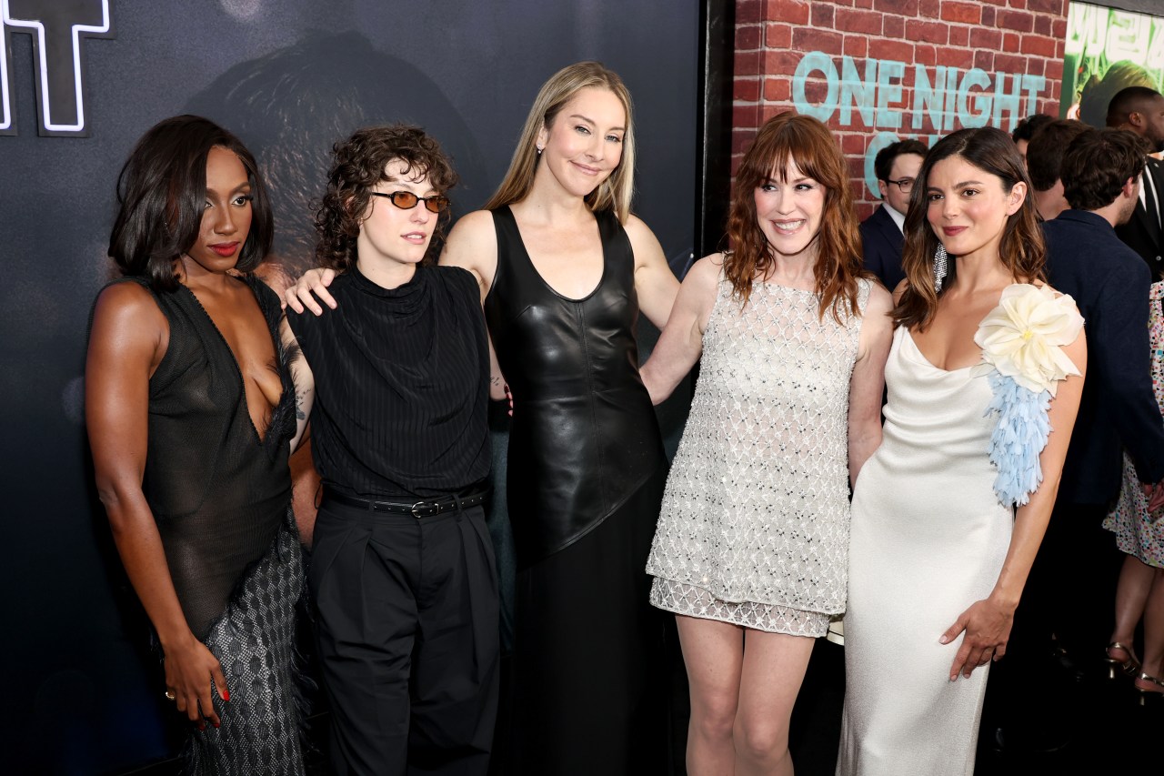 Six people — five women and one person in all black with tinted glasses — pose together smiling at a premiere event in front of a One Night Only sign.