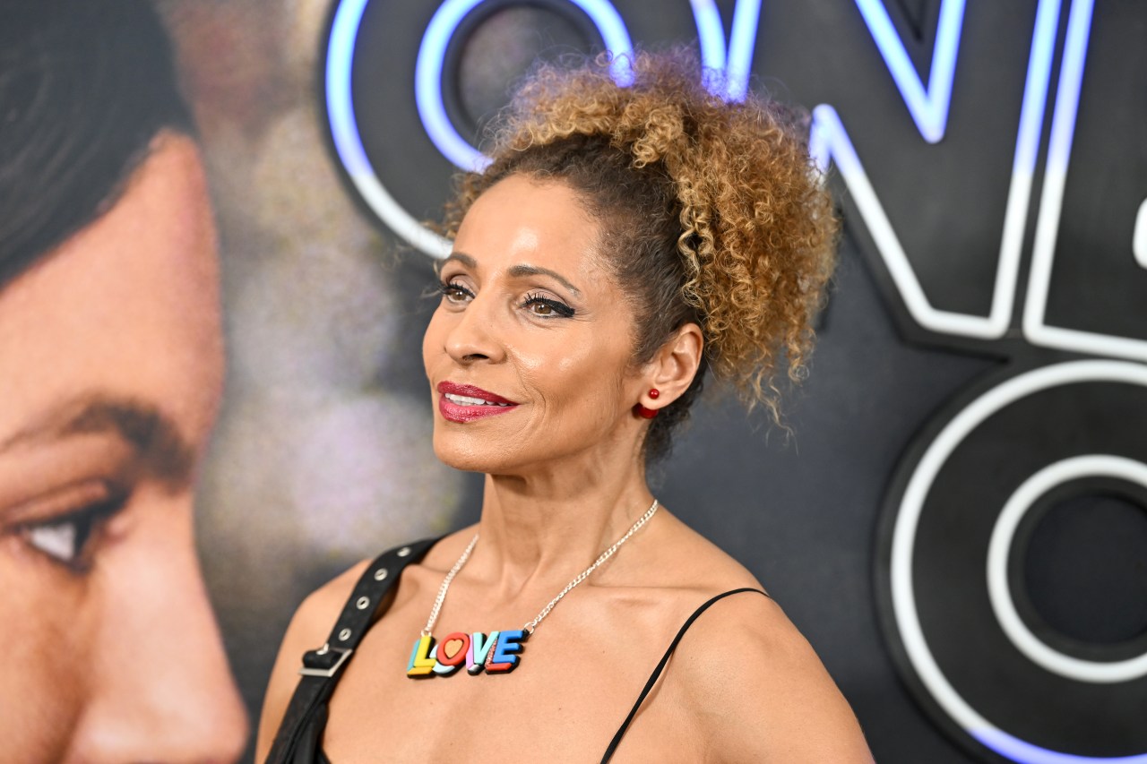 Michelle Hurd with curly updo hairstyle wearing a black dress and a multicolored 'LOVE' necklace at the One Night Only premiere.