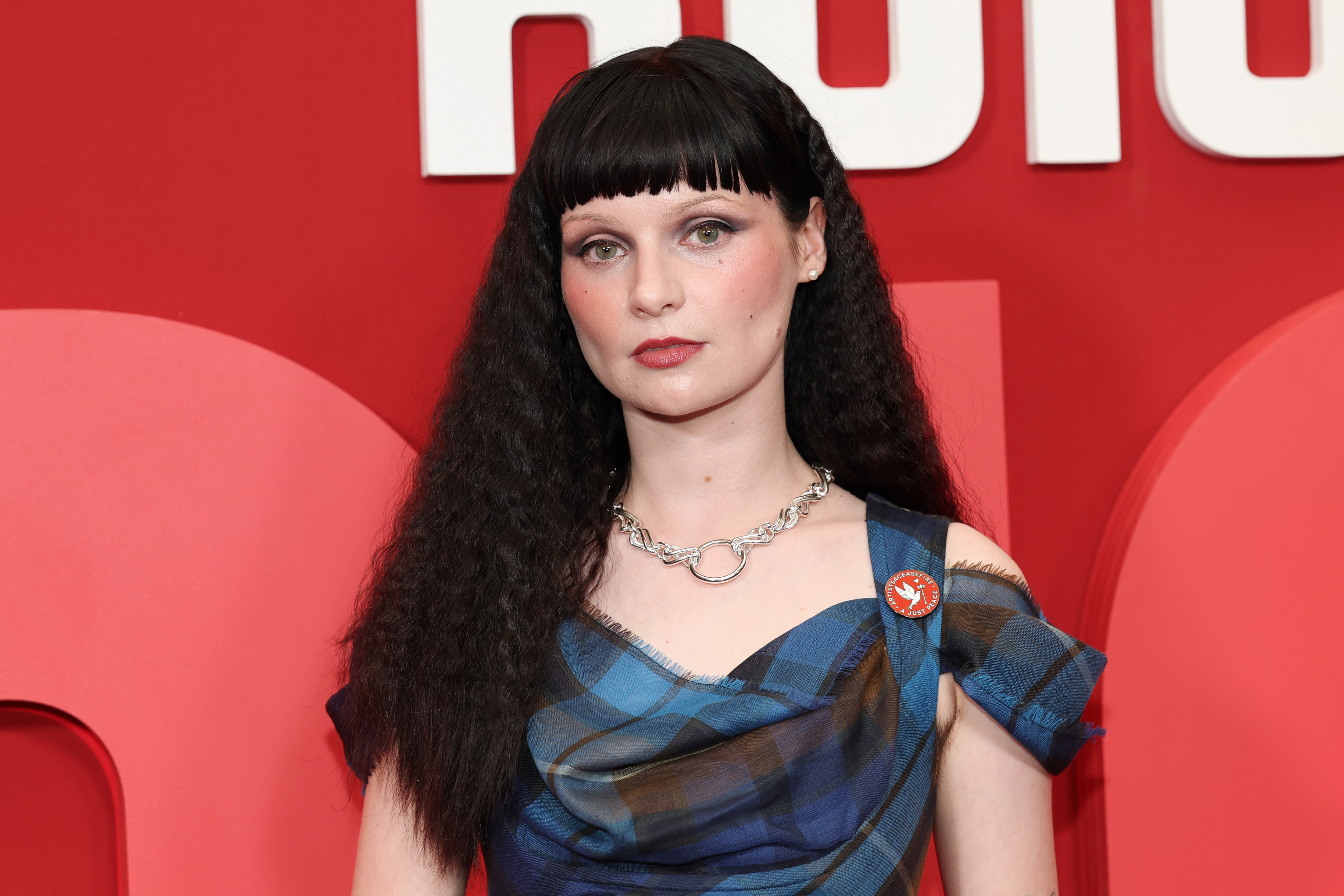 Lola Petticrew in a blue plaid off-shoulder dress with a silver chain necklace at the Hulu Furious premiere in New York City.