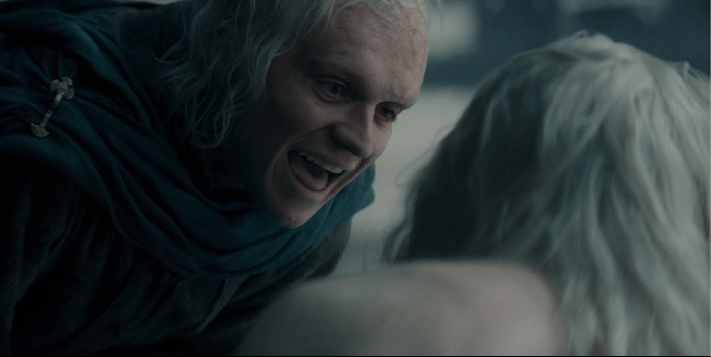 Silver-haired man in dark robes leaning in aggressively toward another person with white hair in a dramatic scene from House of the Dragon.