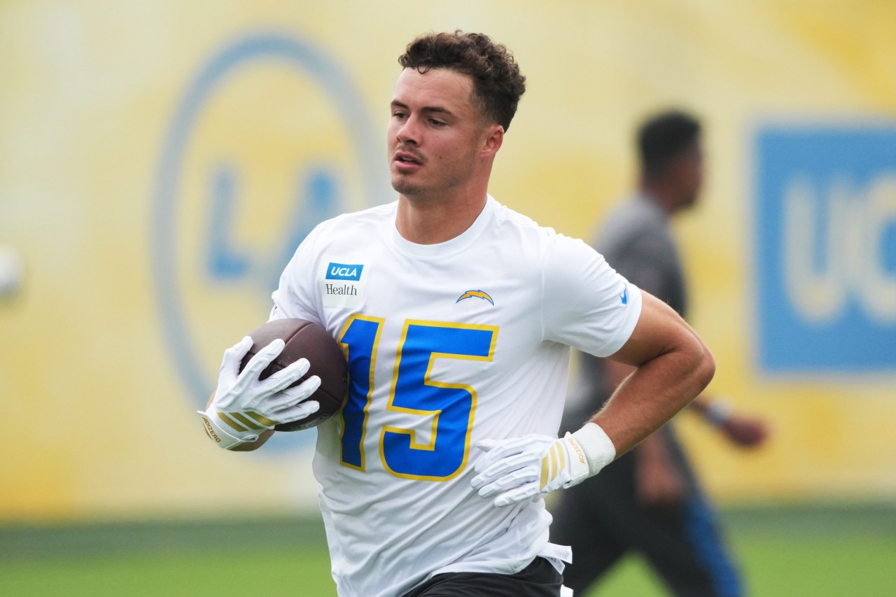 LA Chargers player number 15 in white jersey catching a football during practice, wearing white gloves.