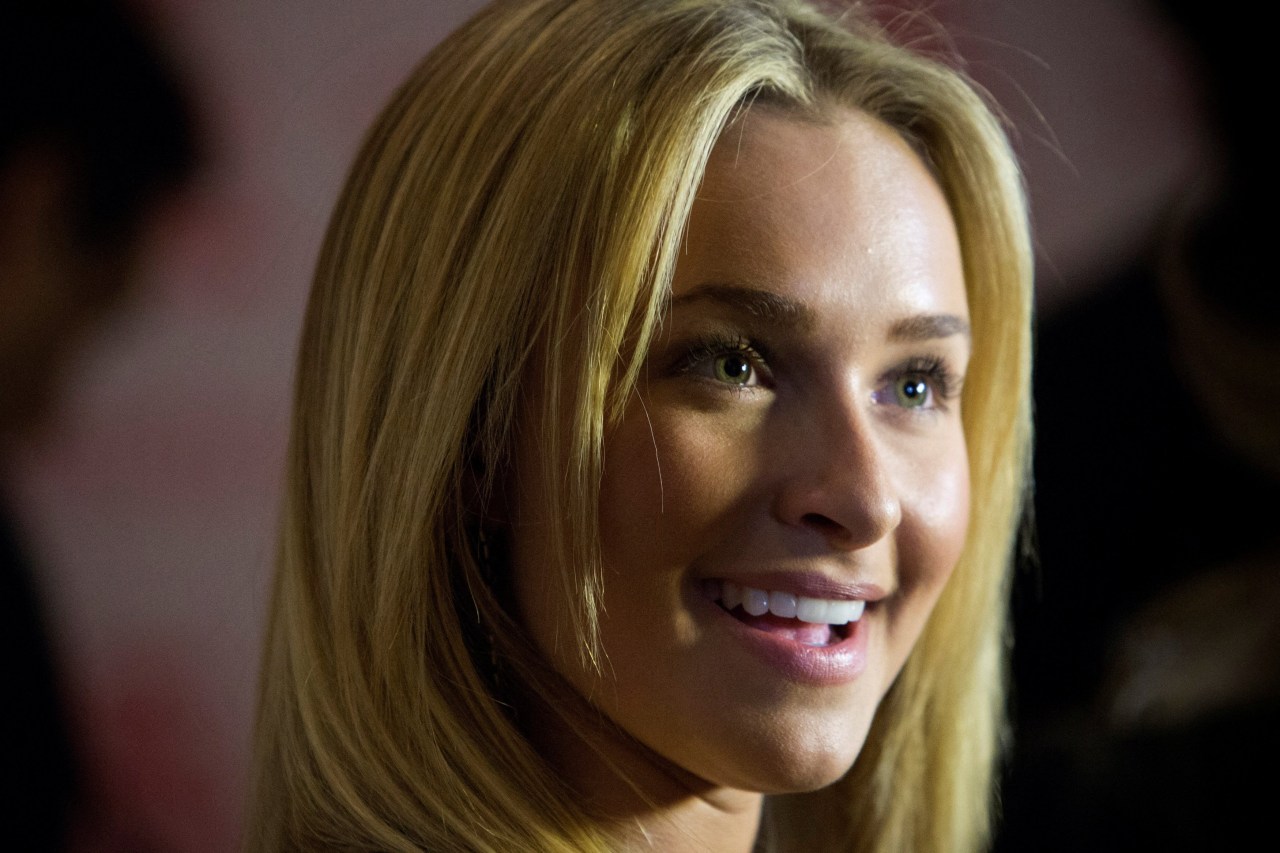 Close-up portrait of a smiling young blonde woman with green eyes and long straight hair.