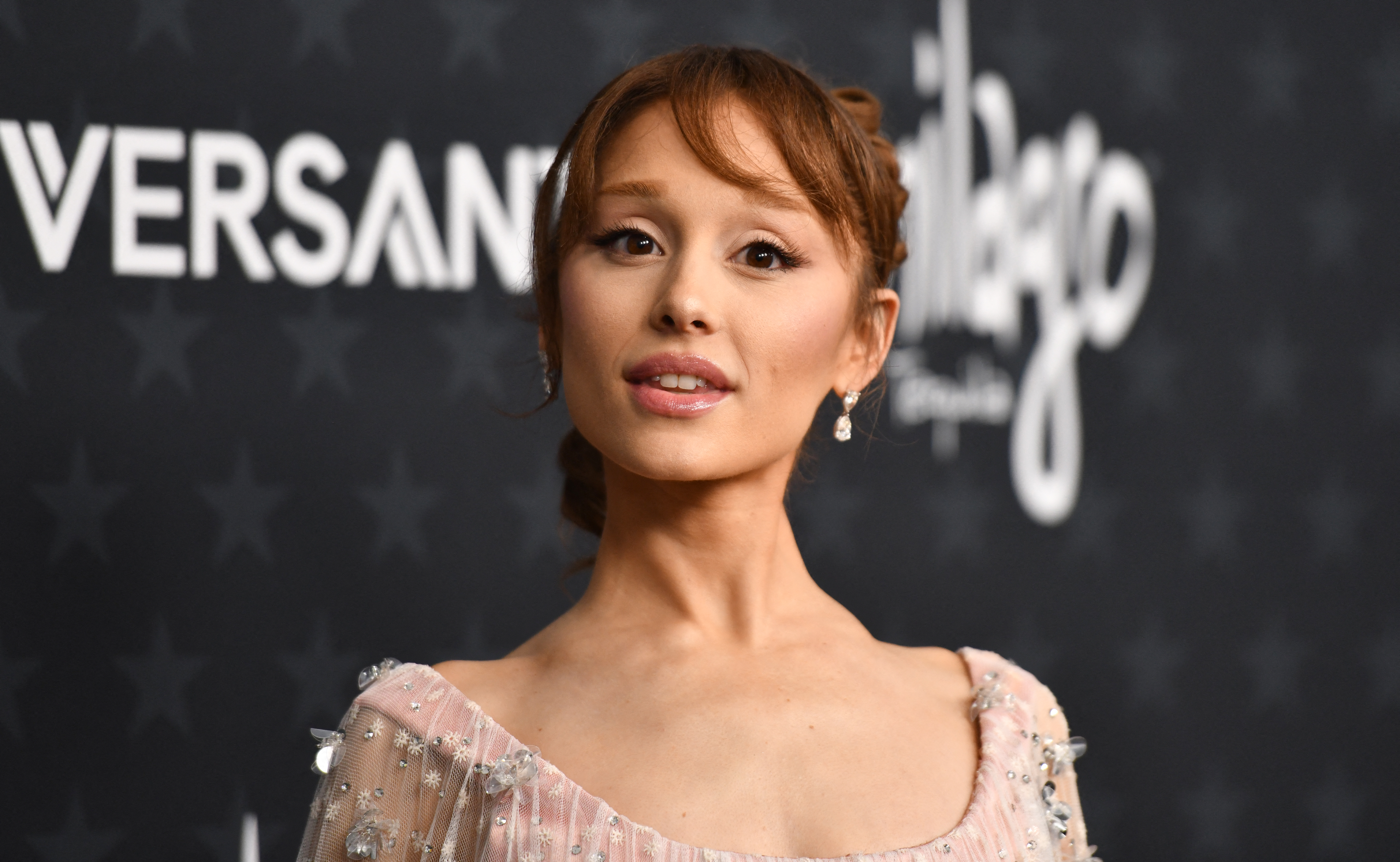 Ariana Grande with auburn updo and bangs in a blush embellished dress at the Critics Choice Awards.