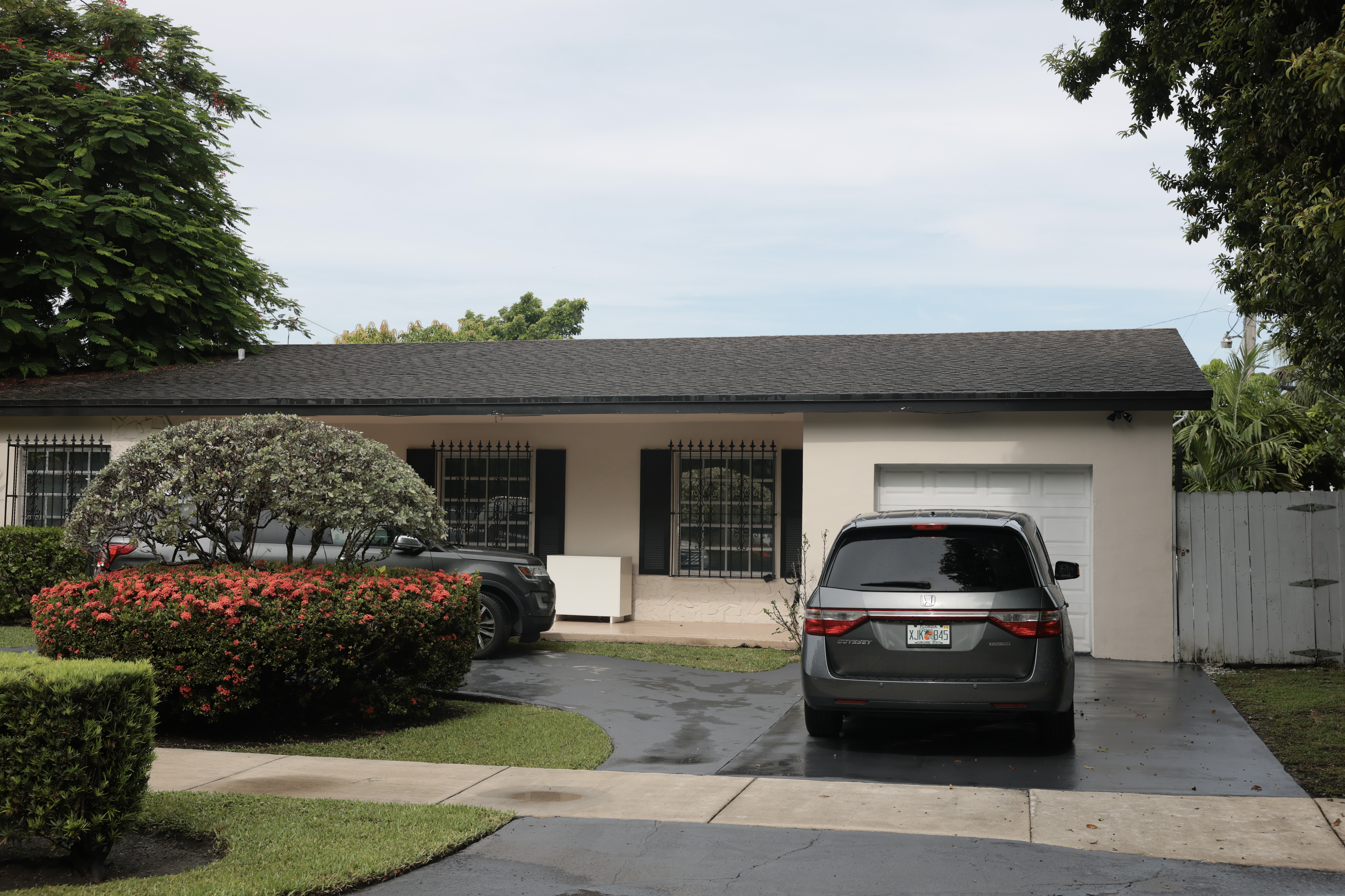 Single-story stucco home with dark roof and two-car driveway in Westchester, Florida, with a gray minivan and black SUV parked outside.