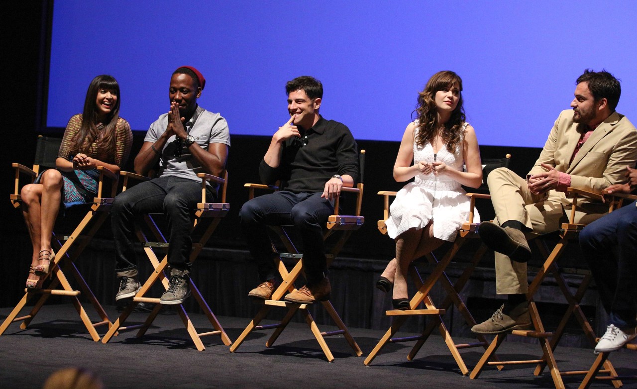 Five actors seated in director's chairs on a darkened stage at the New Girl Season 3 Finale Screening and cast Q&A, smiling and engaged in conversation.