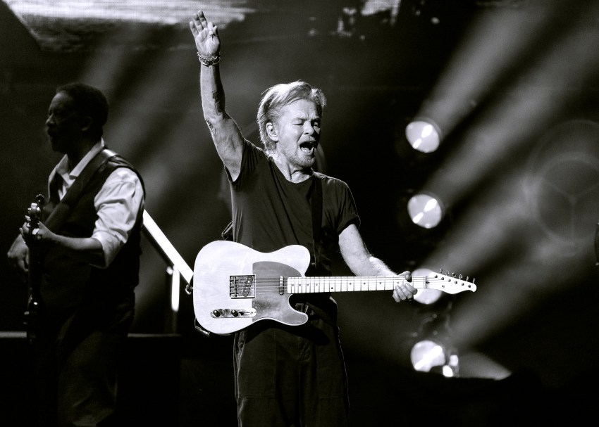 John Mellencamp performing on stage at Acrisure Amphitheater in Grand Rapids, Michigan, in a black and white concert photo