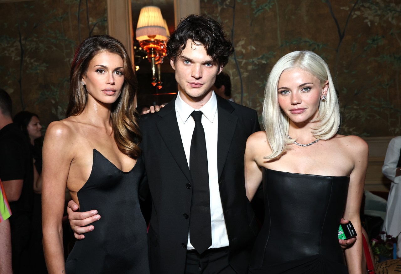Kaia Gerber, Homer Gere, and Hayes Warner pose together at an indoor event, all dressed in black formal attire.