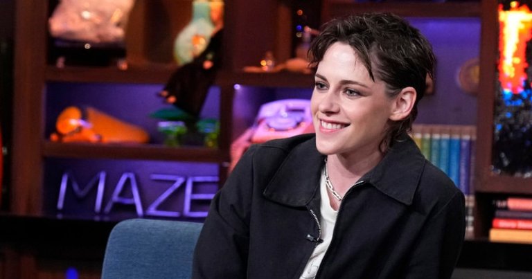 Kristen Stewart smiling and seated in a gray chair on the set of Watch What Happens Live with Andy Cohen.