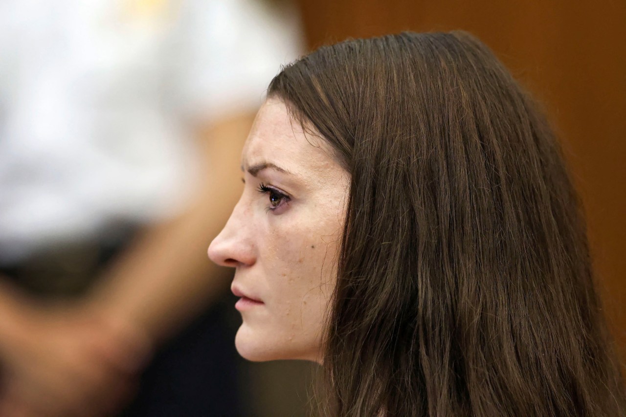 Close-up side profile of a brown-haired woman with teary eyes looking forward in a courtroom.