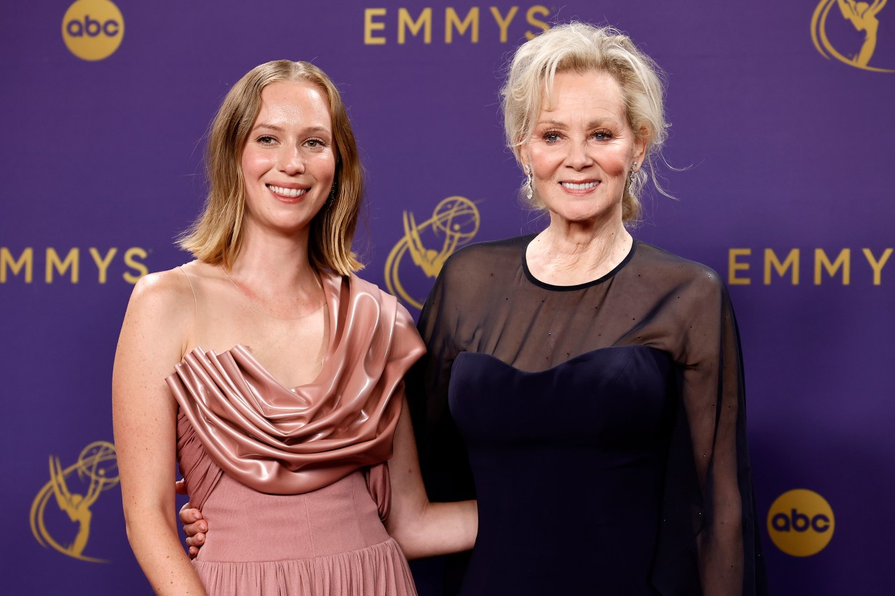 Hannah Einbinder in a pink satin gown and Jean Smart in a navy dress with sheer sleeves pose together at the Emmy Awards press room.