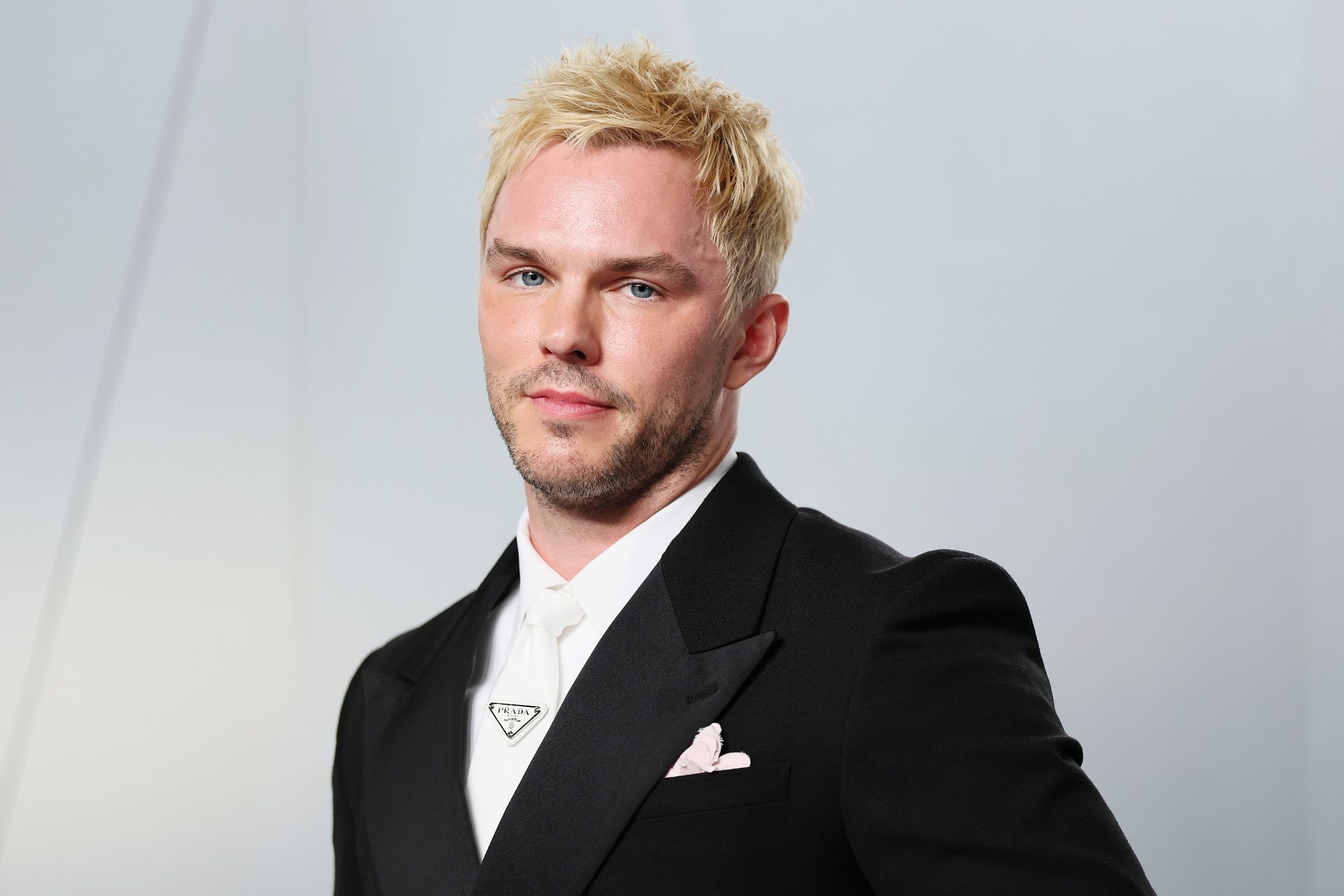 Nicholas Hoult in a black tuxedo with white tie and Prada lapel pin at the 2026 Vanity Fair Oscar Party in Los Angeles.