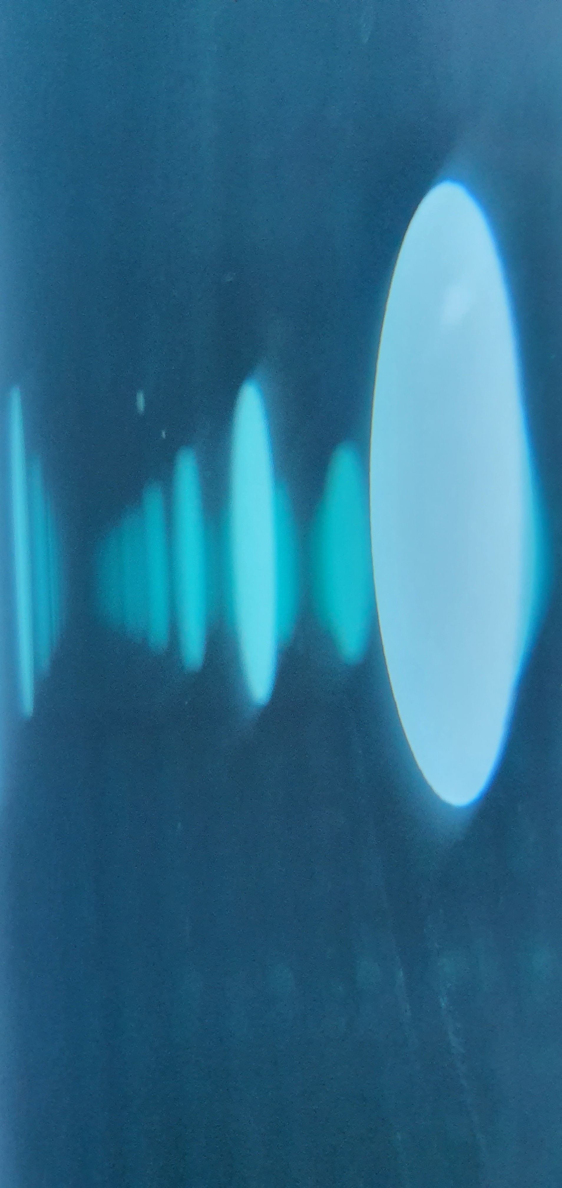 Abstract teal background with a row of glowing cyan oval light spots decreasing in size from right to left.