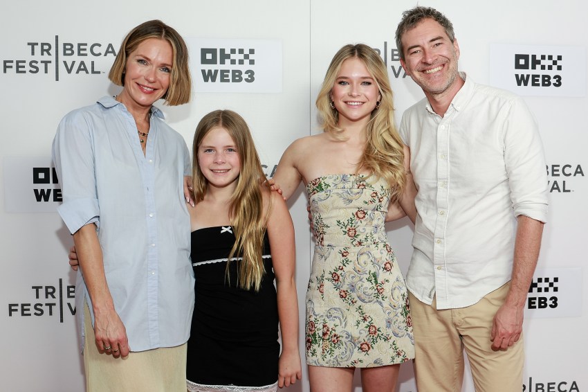 Four people smiling on a Tribeca Festival red carpet backdrop: a woman in a blue shirt, a young girl in black, a teen in a floral dress, and a man in a white shirt.