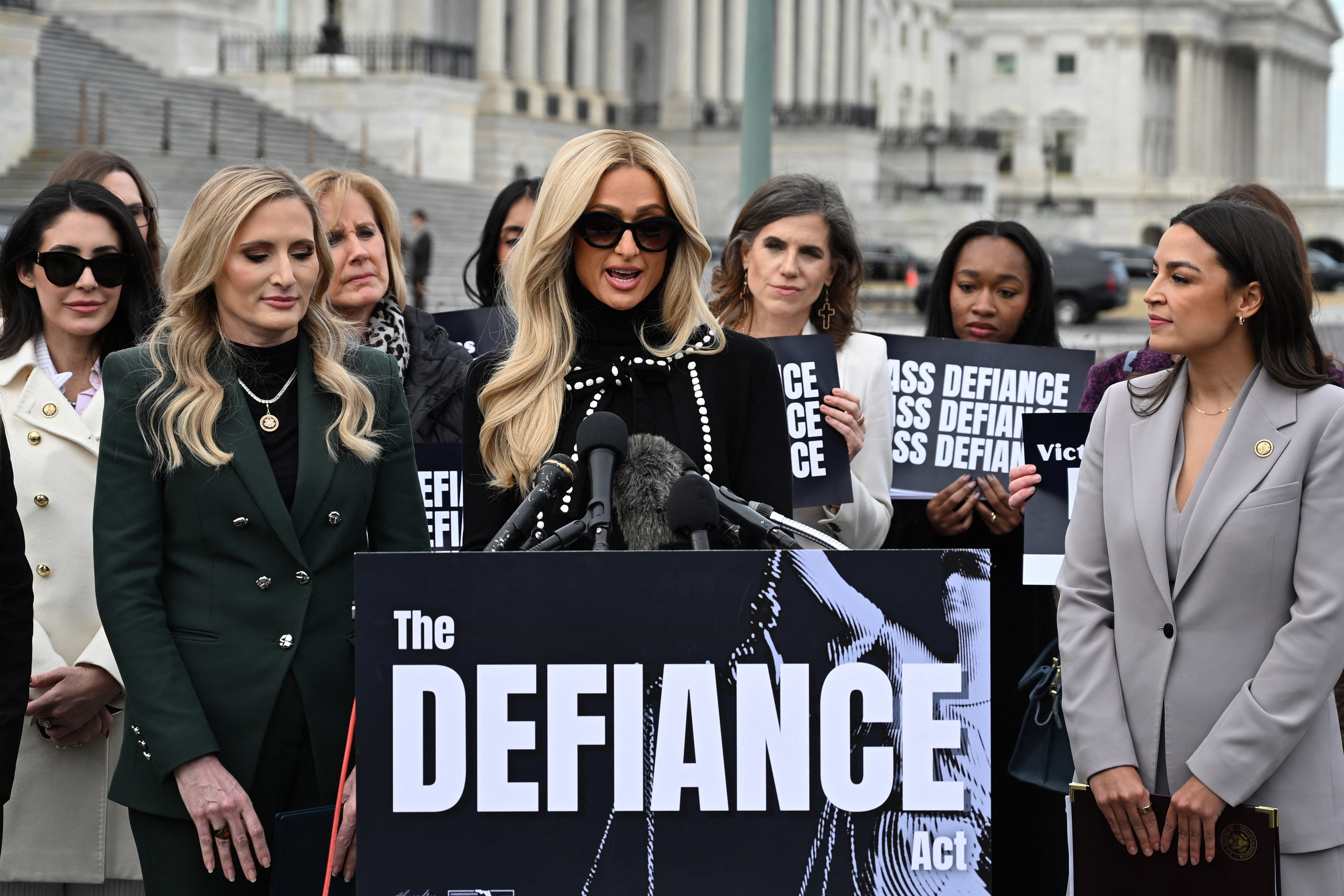Paris Hilton speaking at a Capitol Hill press event alongside Representatives Alexandria Ocasio-Cortez and Laurel Lee in support of the DEFIANCE Act