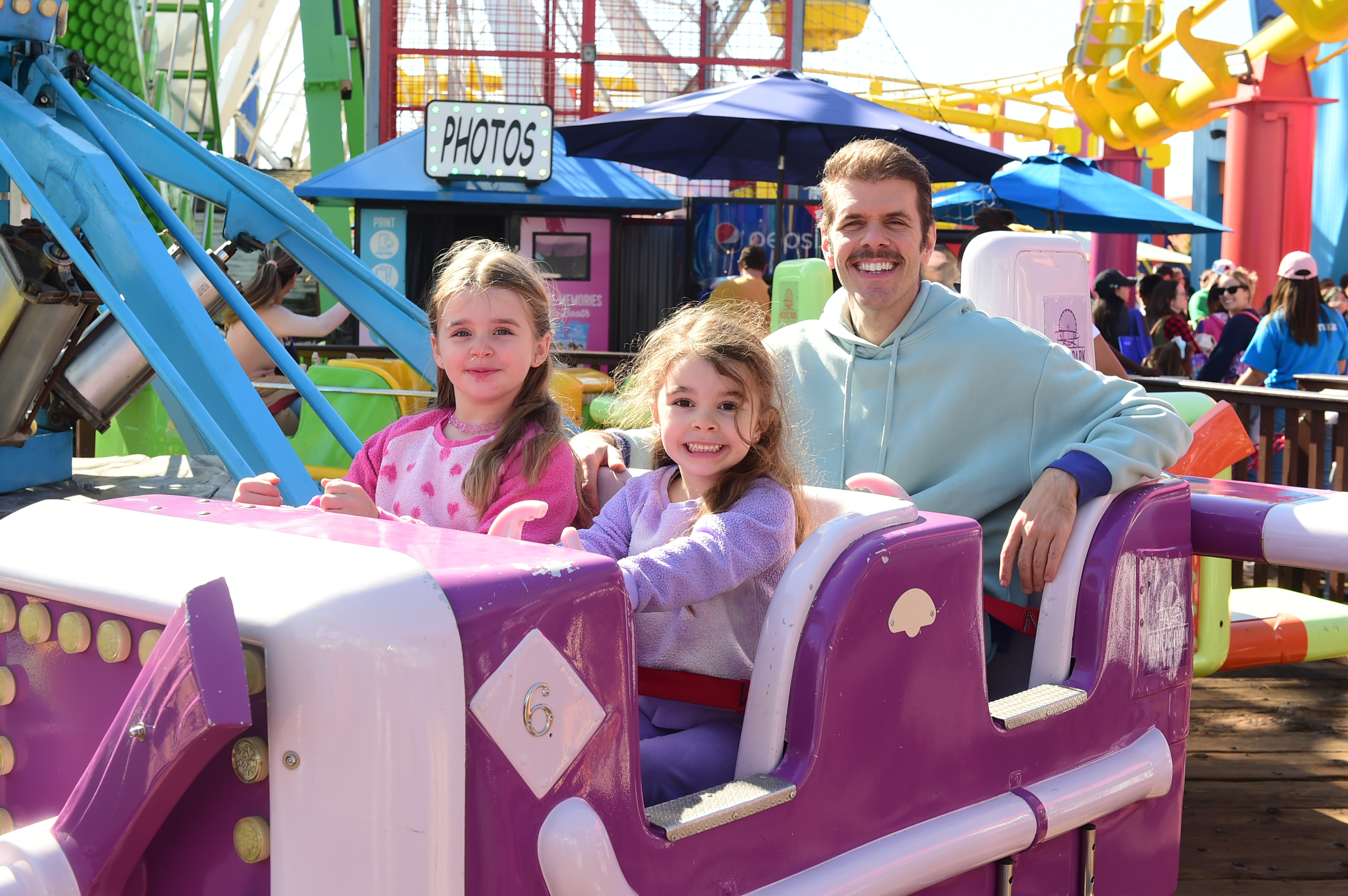 Perez Hilton flanked by his mother Mia Alma Lavandeira and sister Mayte Amor at an outdoor event on the Santa Monica Pier