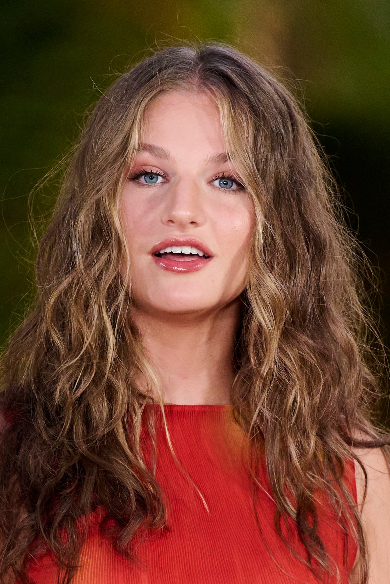 Crown Princess Leonor of Spain with long wavy brunette hair and blue eyes, wearing a red sleeveless top, at Marivent Palace in Mallorca.