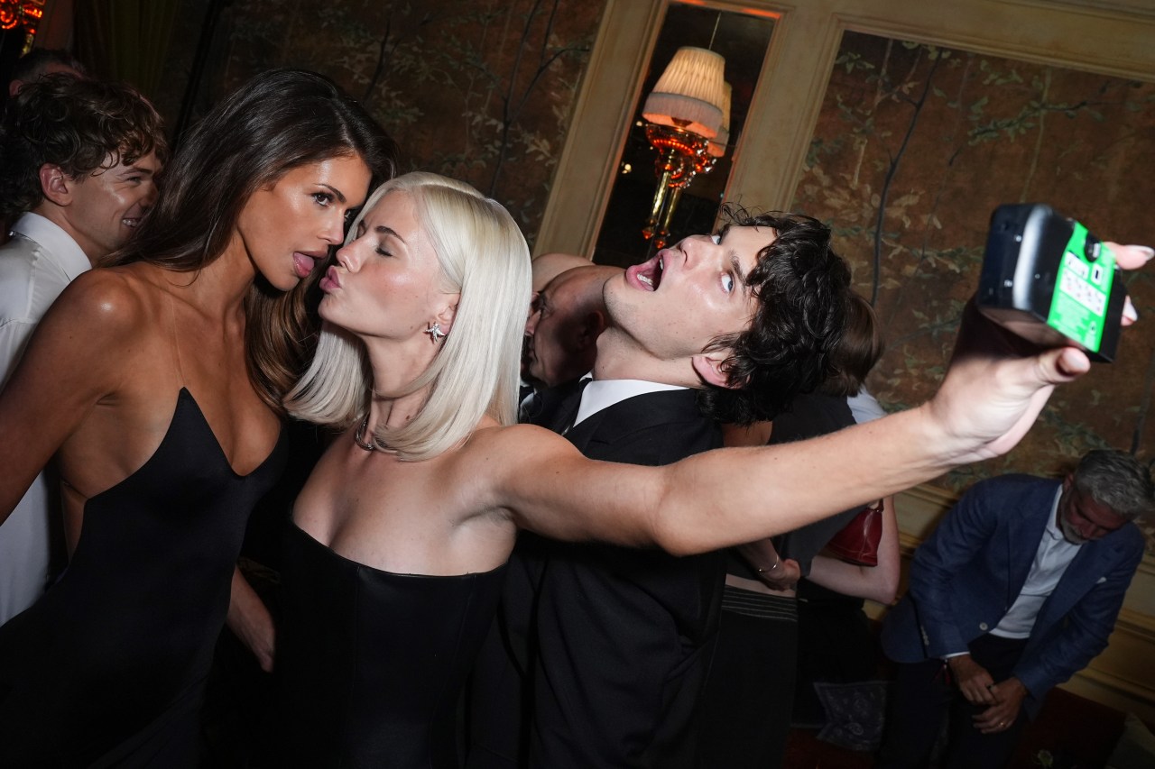 Kaia Gerber, Hayes Warner, and Homer Gere pose for a selfie at an upscale party venue, making silly faces for the camera.