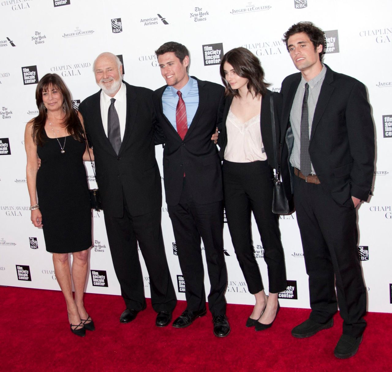Rob Reiner and a woman in black dress stand with three young adults on a red carpet at the Chaplin Award Gala, NYC.