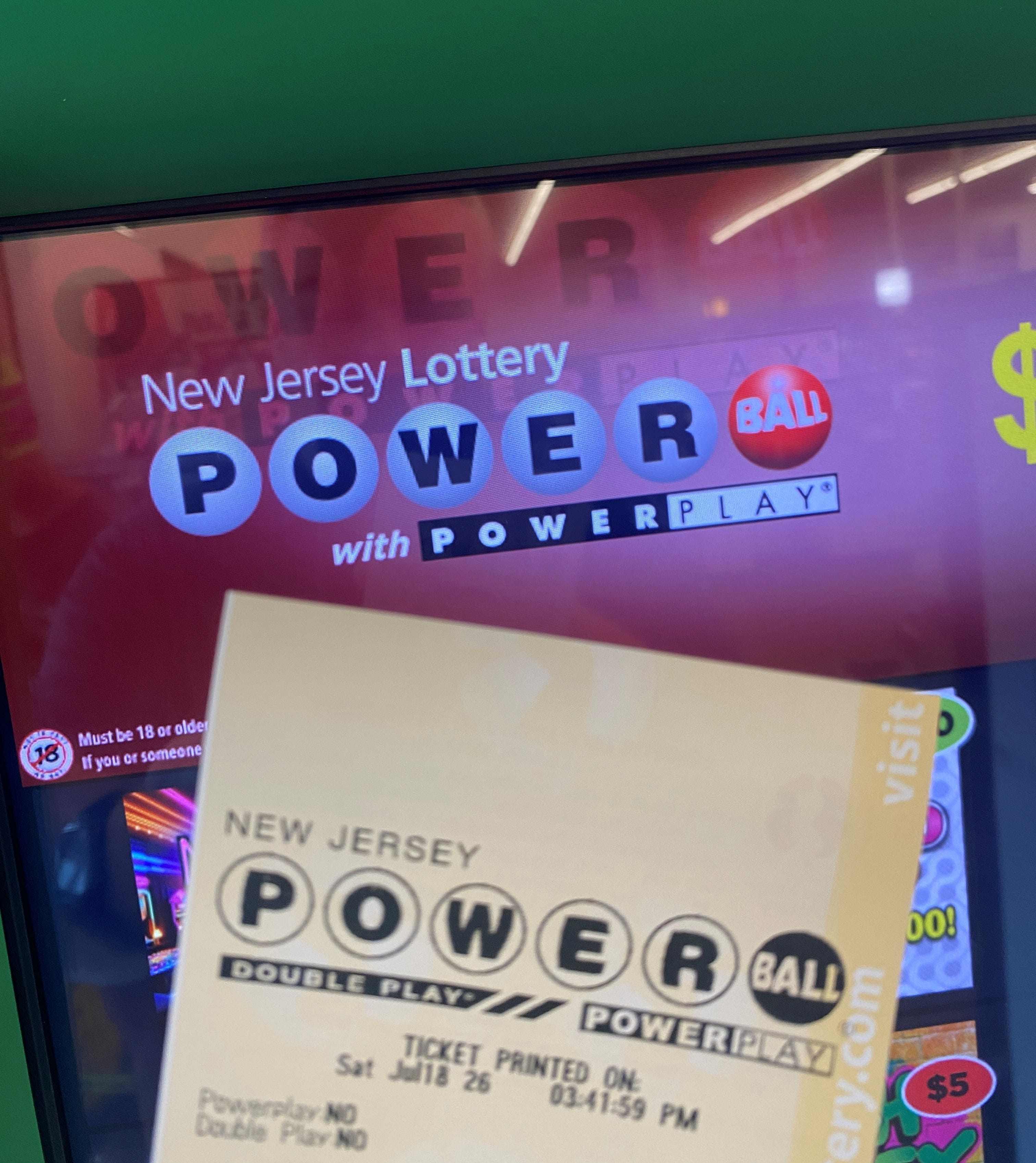 A New Jersey Powerball lottery ticket held in front of a Powerball vending machine screen showing the game logo.