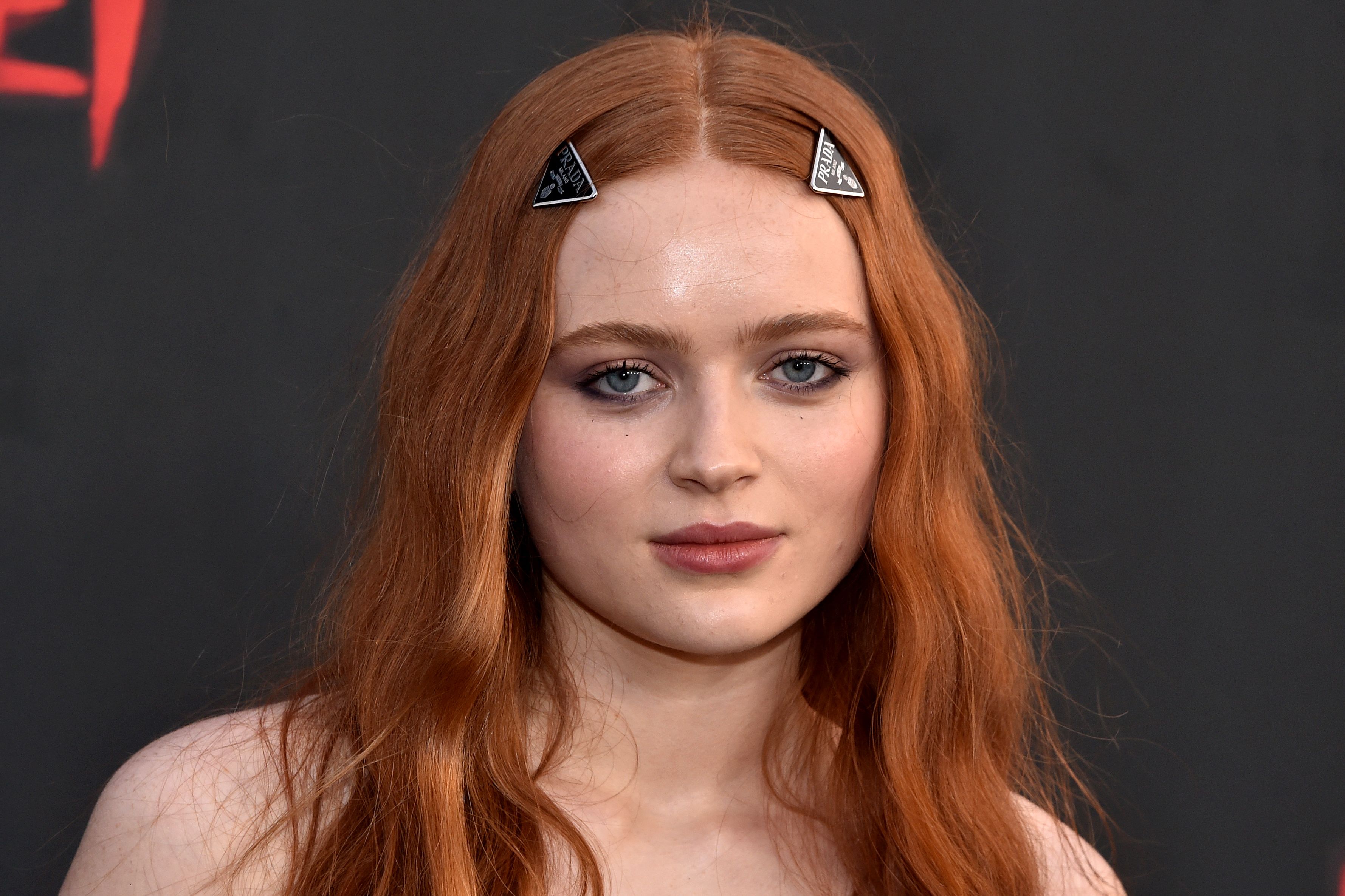 Sadie Sink with long auburn hair and Prada triangle hair clips at the Fear Street Trilogy Netflix premiere in Los Angeles.