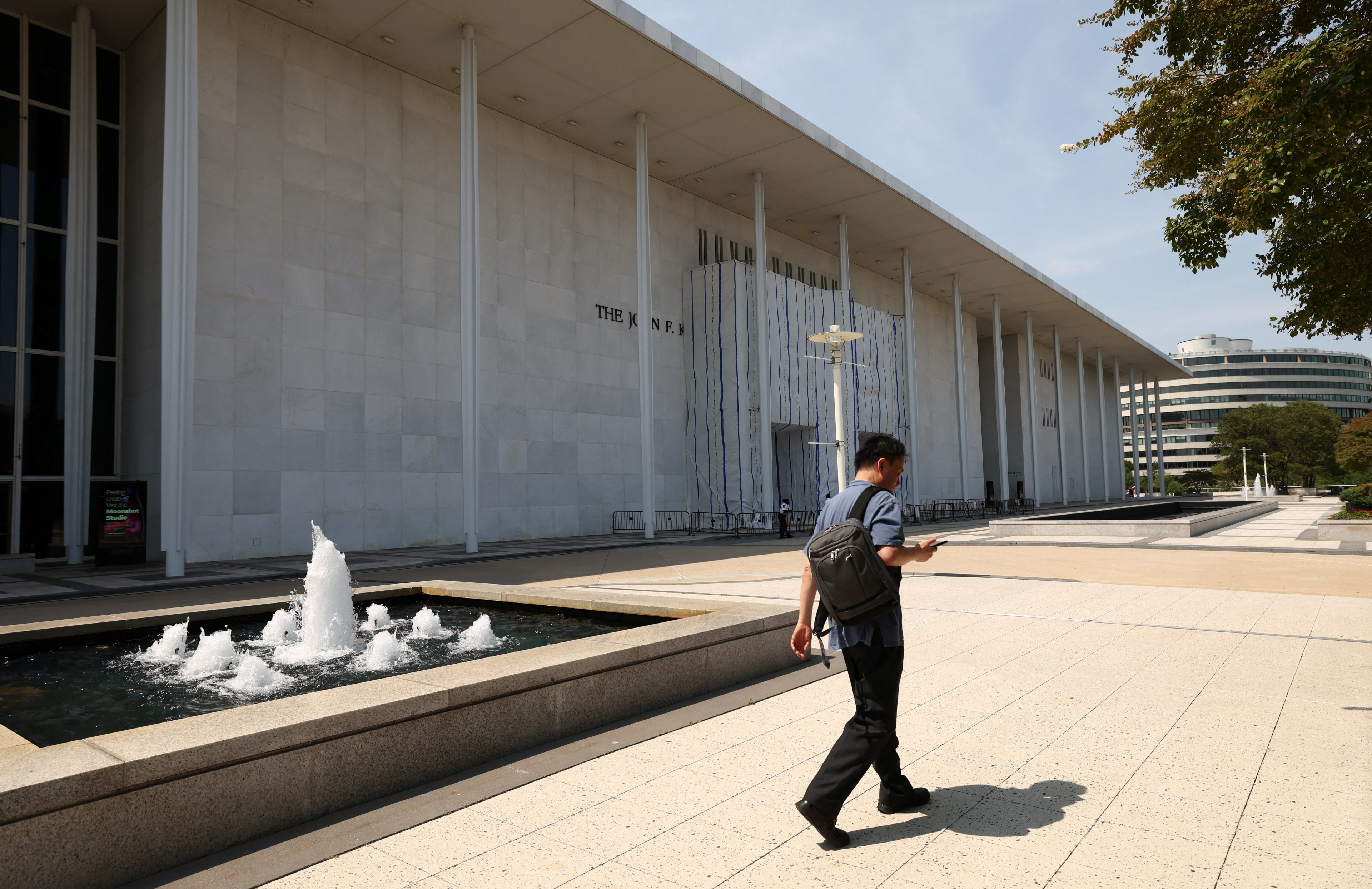 A man walking along the front of the John F. Kennedy Center for the Performing Arts in Washington, D.C.