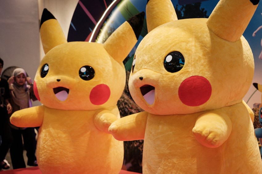 Two people in Pikachu mascot costumes posing at Pokemon GO Fest Global event inside a mall in Jakarta