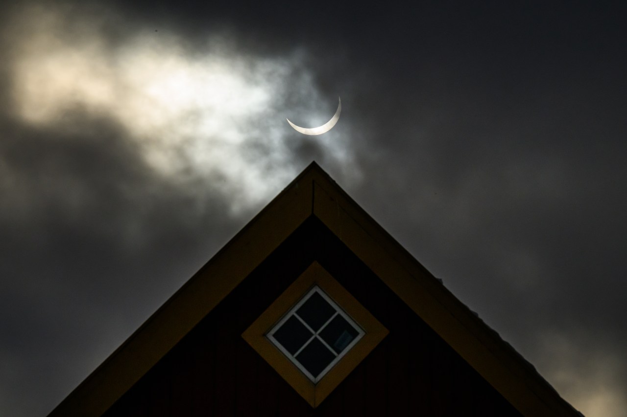 A traditional Greenlandic home silhouetted against the sky during a partial solar eclipse in Nuuk, Greenland
