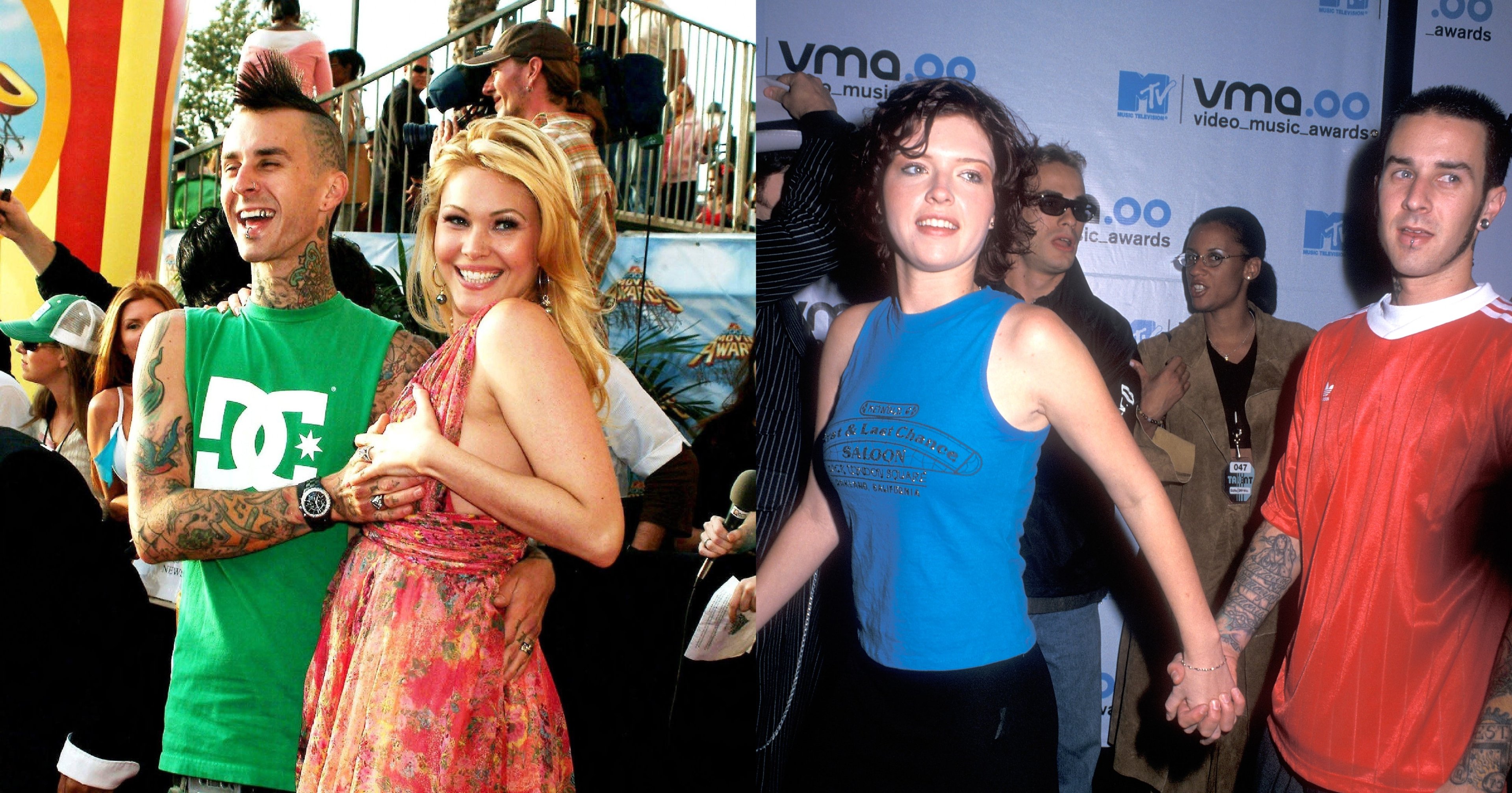 Travis Barker in a green DC shirt with tattoos and a mohawk stands with blonde woman in a pink floral dress at an outdoor red carpet event.