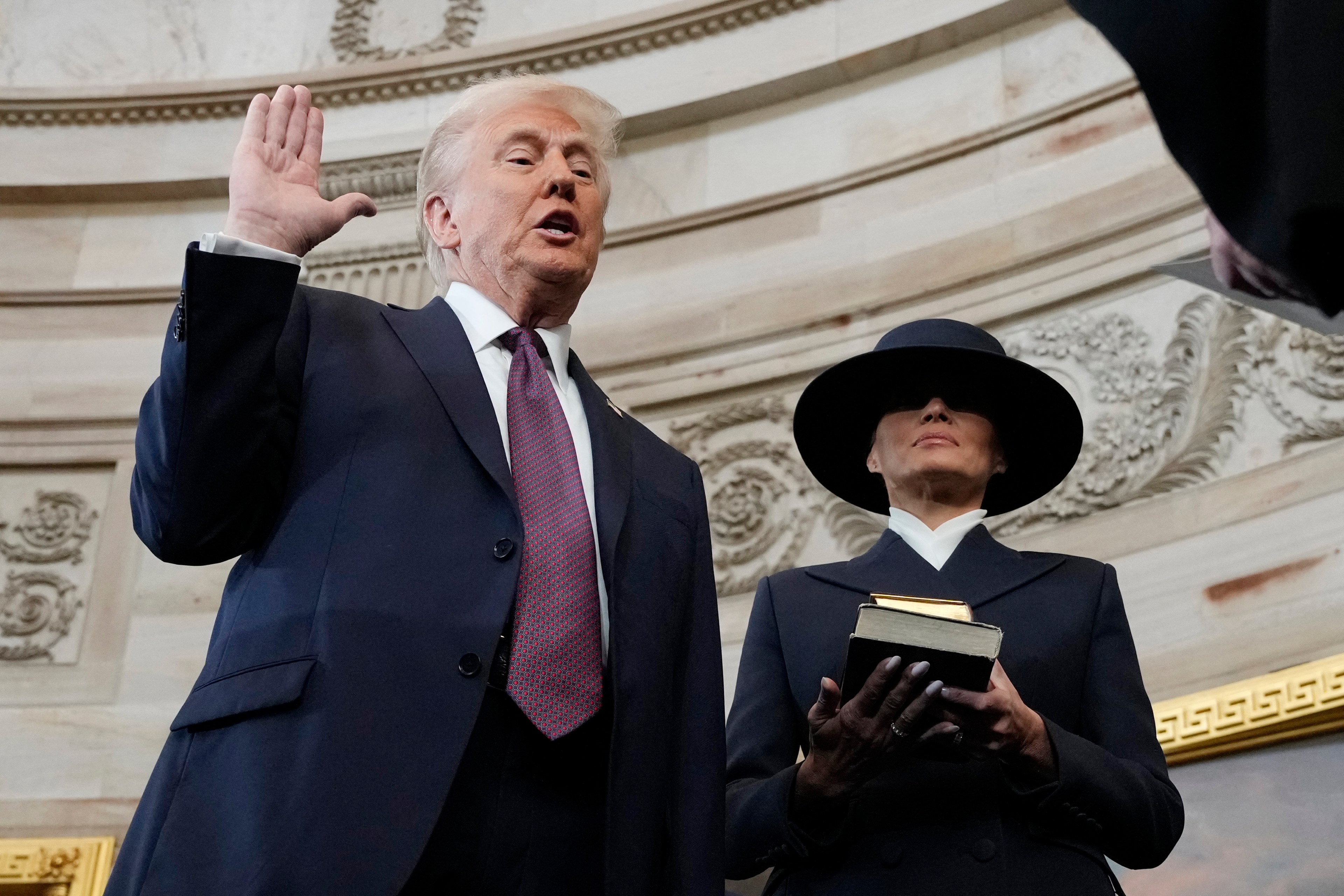 Donald Trump being sworn in as president by Chief Justice John Roberts while Melania Trump holds a Bible in the U.S. Capitol Rotunda