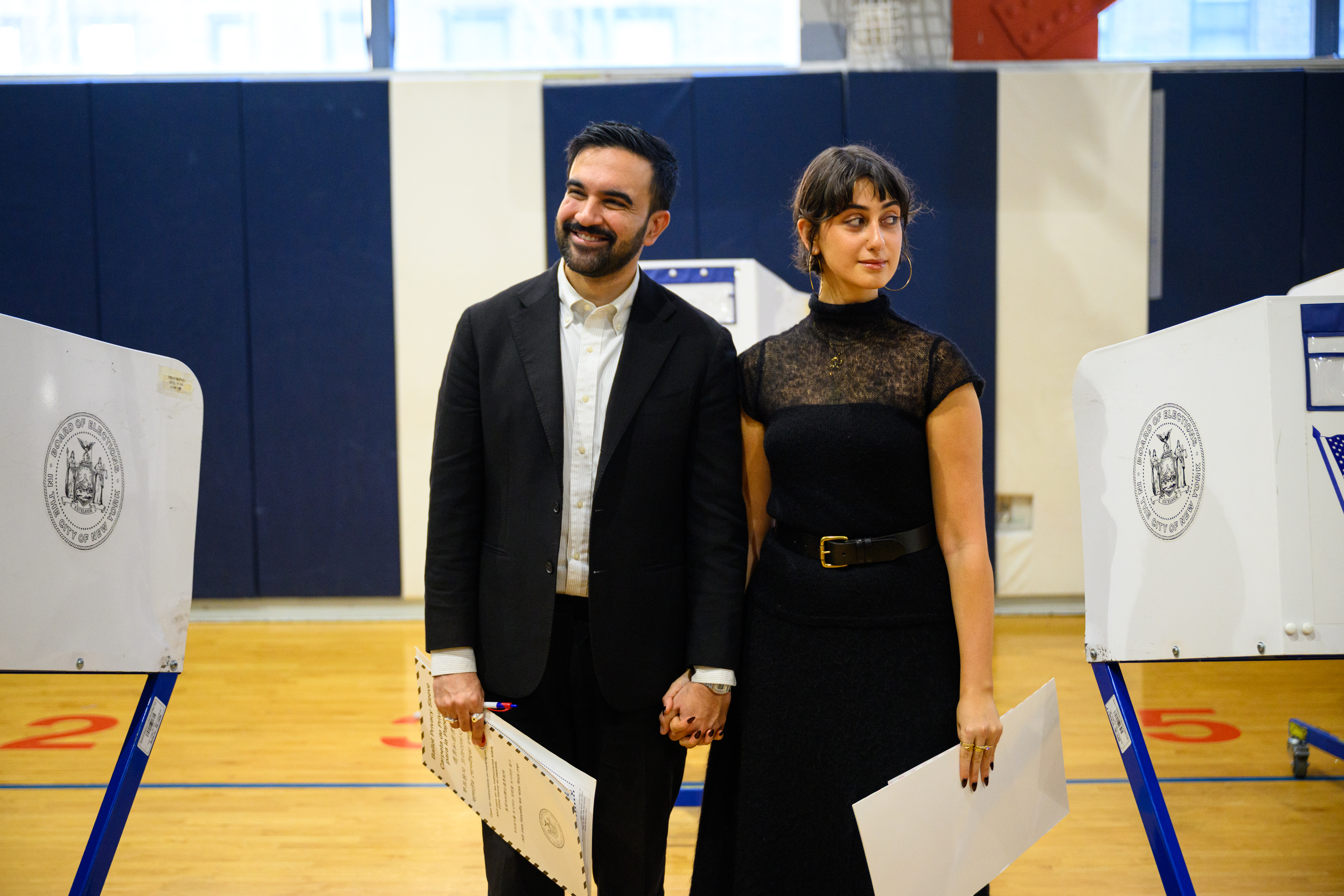 Zohran Mamdani and Rama Duwaji posing for media outside a polling location in Queens, New York