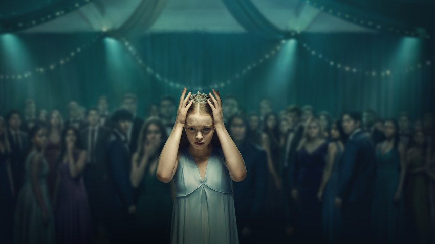 Carrie White holding a tiara to her head as the prom crowd stares